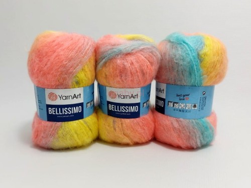 Trzy motki puszystej włóczki YarnArt Bellissimo numer koloru 1413 w pastelowych odcieniach łososiowego, żółtego i błękitnego na białym tle.
