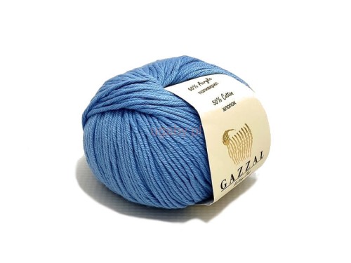 Motek niebieskiej włóczki Gazzal Baby Cotton XL 3423 na jasnym tle, widoczny gładki splot i banderola ugaby.pl.